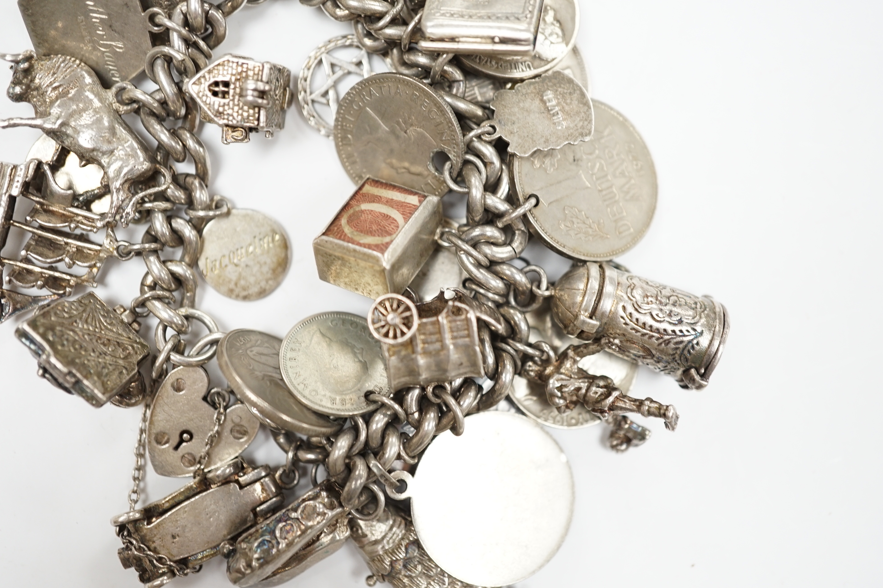 A silver charm bracelet, hung with assorted mainly white metal charms including tankard and Knight's helmet, two 'melted' ingots and a silver medallion.